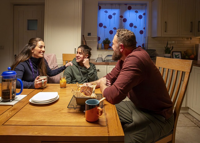 Social worker, teenage boy and foster carer sat at a kitchen table